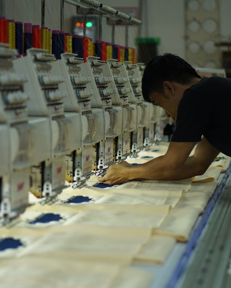 Operator mesin bordir komputer mengerjakan bordir logo di workshop Syamanah